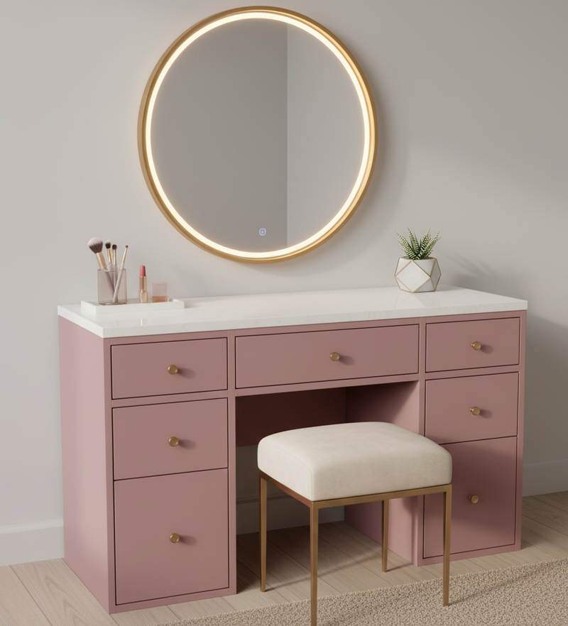 Pink vanity with round mirror, drawers, and stool in a room setting.